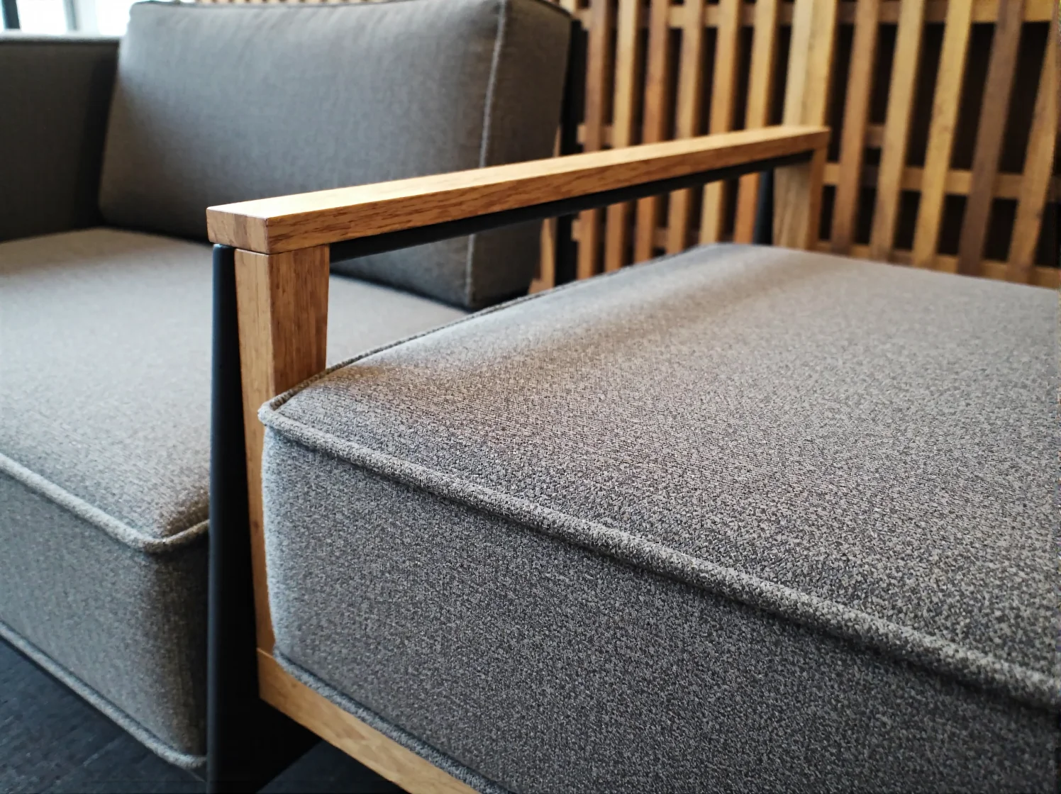 Szara sofa coworkingowa z drewnianym podłokietnikiem dębowym